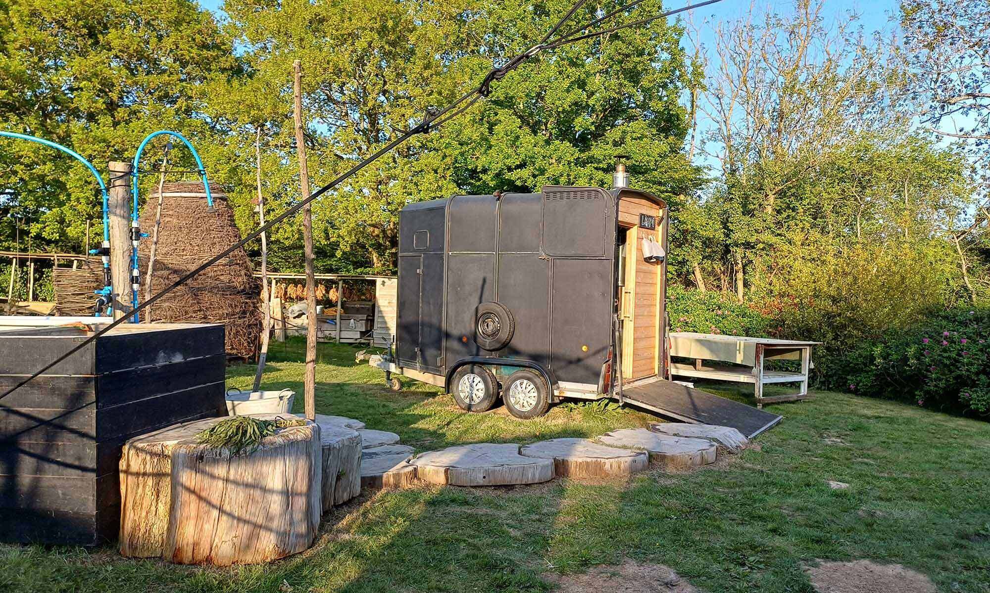 The LogJam Sauna horse-box trailer exterior with wooden door, set in East Sussex woodland